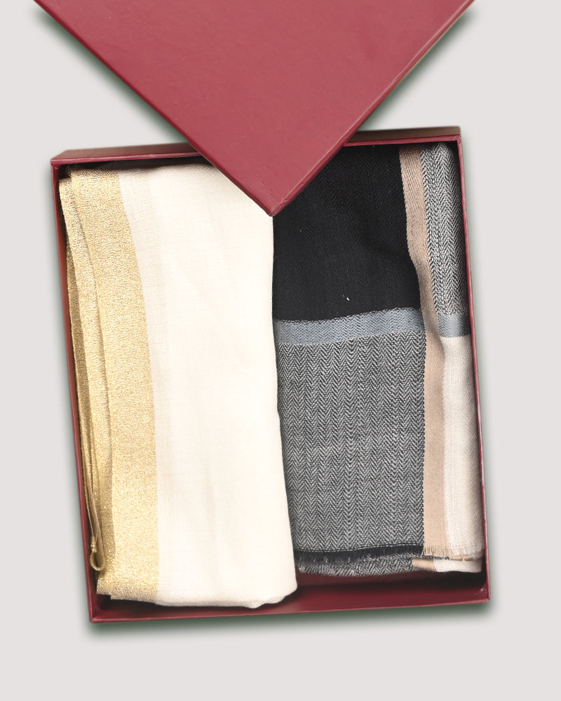 Two folded shawls in a box, one primarily white and the other with a multicolor pattern, likely wool or wool-silk blend.

